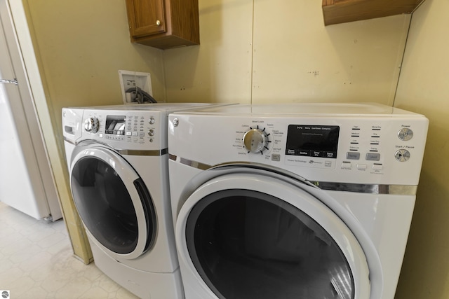 clothes washing area featuring cabinet space and washer and clothes dryer