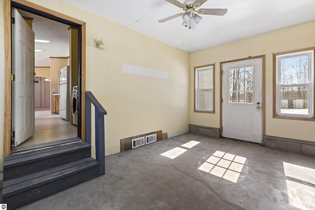 entryway with unfinished concrete flooring, a ceiling fan, and visible vents