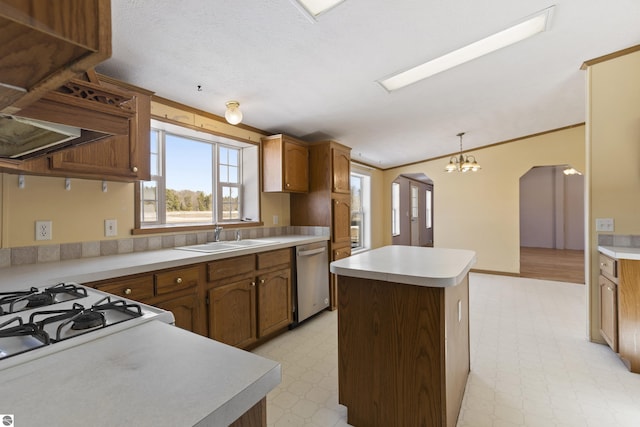 kitchen featuring light floors, a kitchen island, arched walkways, a sink, and dishwasher