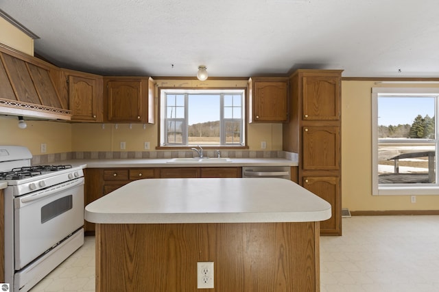 kitchen with brown cabinets, a sink, light floors, light countertops, and white range with gas stovetop