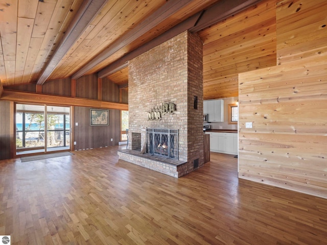 unfurnished living room featuring wood ceiling, wood finished floors, a brick fireplace, and wood walls