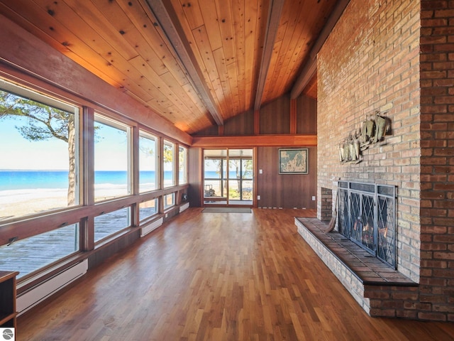 unfurnished living room with lofted ceiling with beams, a baseboard heating unit, wood finished floors, wooden ceiling, and a brick fireplace