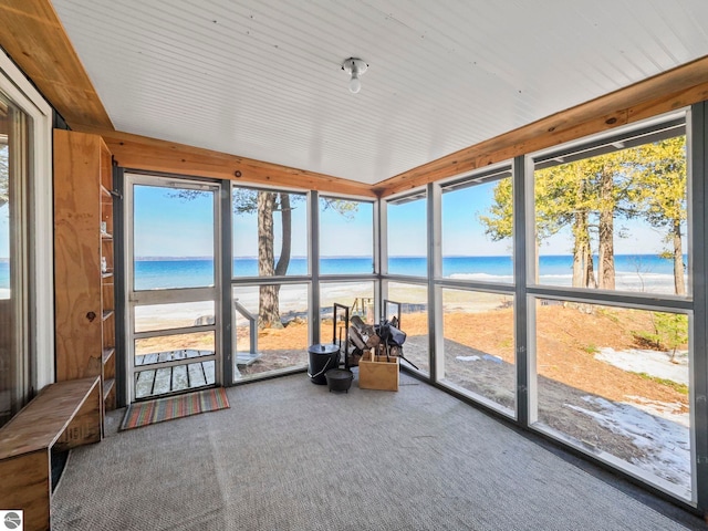 sunroom featuring a beach view and a water view