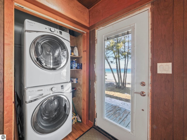 laundry area featuring a view of the beach, wood finished floors, laundry area, and stacked washing maching and dryer