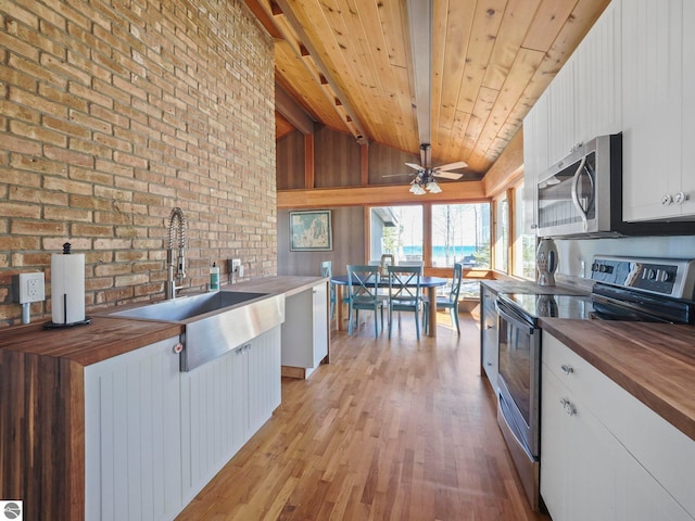 kitchen featuring a sink, white cabinetry, light wood-style floors, appliances with stainless steel finishes, and wooden counters