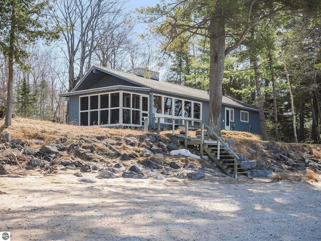 view of front of home with stairs and a sunroom