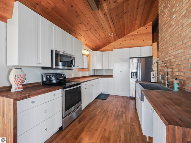 kitchen with a sink, wood counters, appliances with stainless steel finishes, and dark wood-style flooring