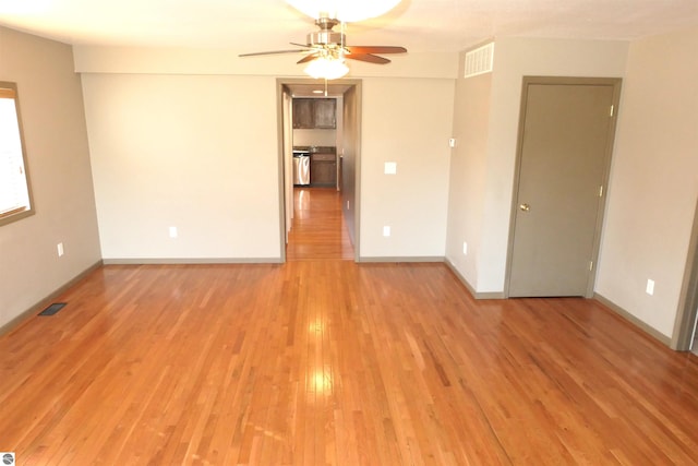 spare room featuring light wood-type flooring, baseboards, visible vents, and a ceiling fan