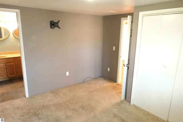 unfurnished bedroom featuring a sink, a closet, carpet, and ensuite bathroom