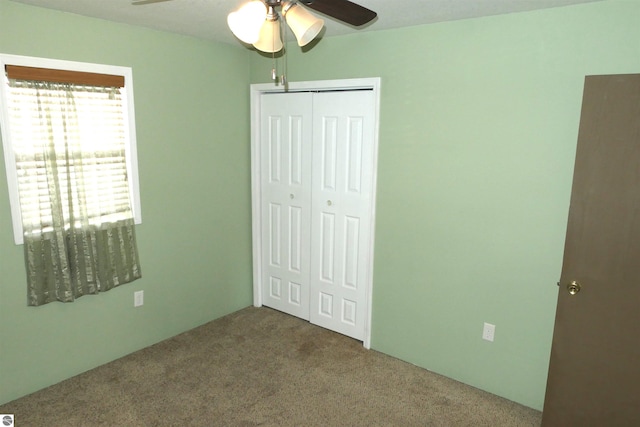 unfurnished bedroom featuring a closet, carpet floors, and a ceiling fan