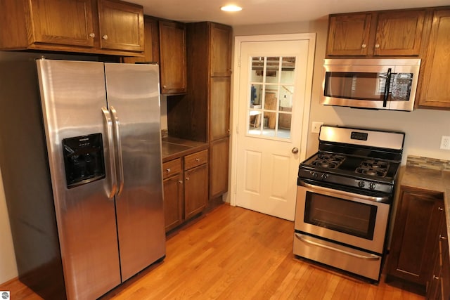 kitchen featuring recessed lighting, light wood-type flooring, brown cabinets, and appliances with stainless steel finishes