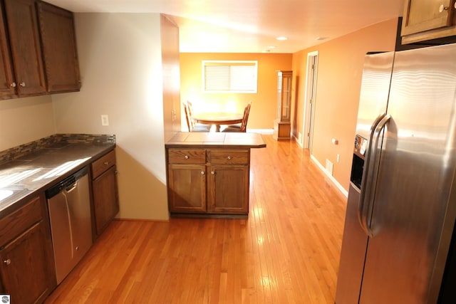 kitchen featuring visible vents, light wood-style floors, appliances with stainless steel finishes, a peninsula, and brown cabinetry