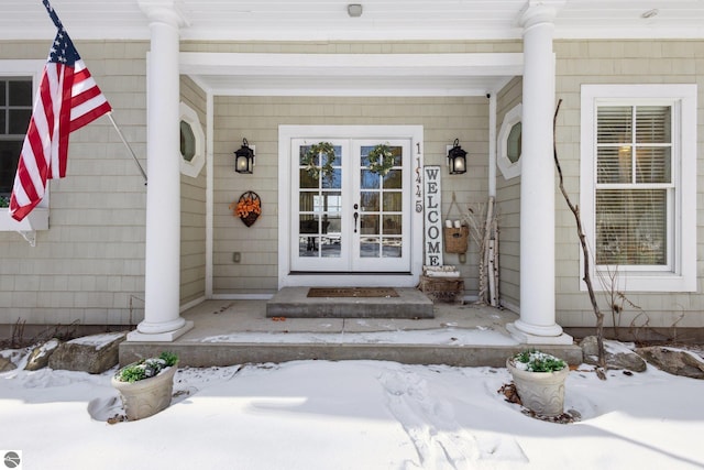 snow covered property entrance with french doors and a porch