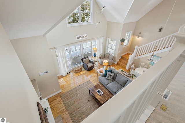 living room featuring stairway, plenty of natural light, high vaulted ceiling, and wood finished floors