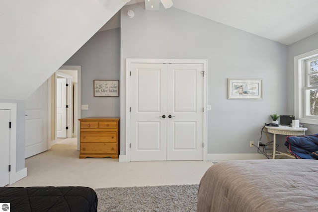 carpeted bedroom with a closet, lofted ceiling, baseboards, and a ceiling fan