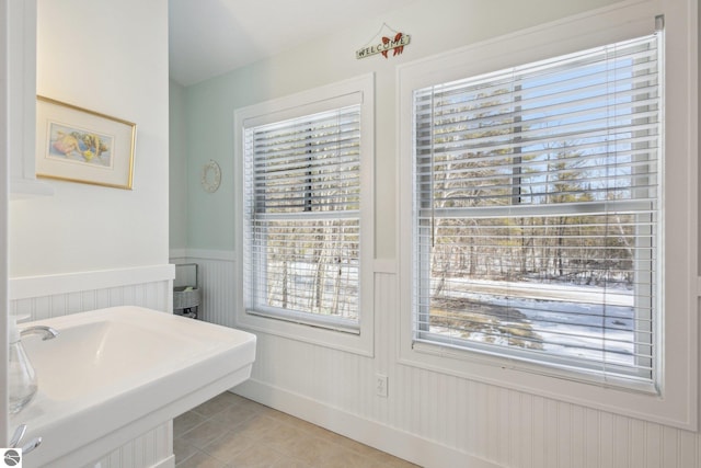 bathroom with tile patterned flooring, a wainscoted wall, and a sink