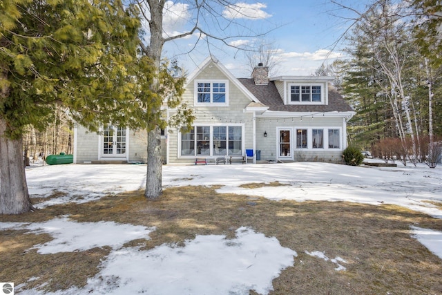 shingle-style home with a shingled roof, a patio, french doors, and a chimney