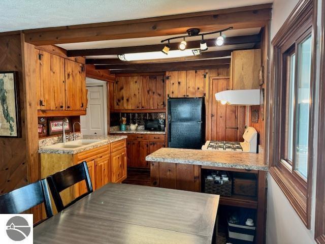 kitchen with light countertops, brown cabinets, freestanding refrigerator, and a sink