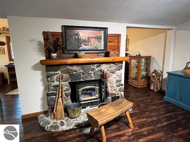 details featuring a fireplace, a textured ceiling, baseboards, and wood finished floors