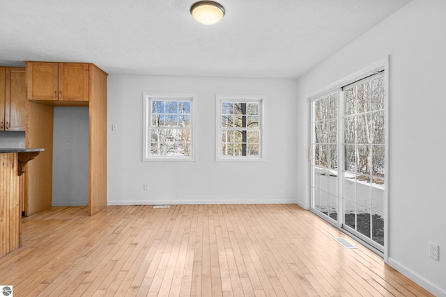 unfurnished living room featuring light wood finished floors, visible vents, and baseboards