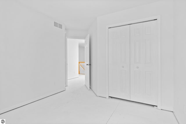 unfurnished bedroom with visible vents, concrete flooring, and a closet