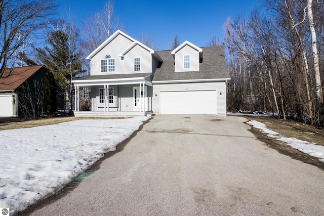 traditional home featuring aphalt driveway, a porch, an attached garage, and a shingled roof