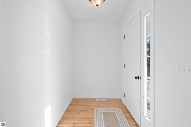 hall with visible vents, light wood-style floors, and baseboards