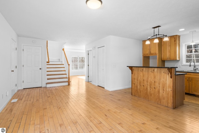 kitchen featuring a breakfast bar, light wood-style flooring, decorative light fixtures, and a wealth of natural light