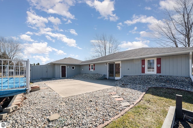 ranch-style house with a shingled roof and a patio area