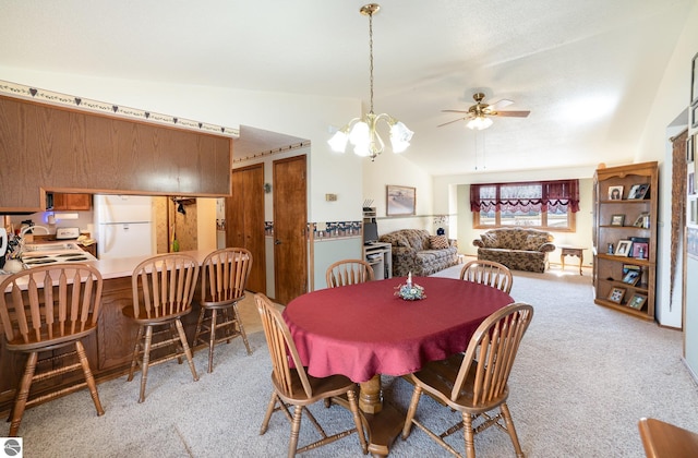 dining area with light carpet, ceiling fan with notable chandelier, and vaulted ceiling