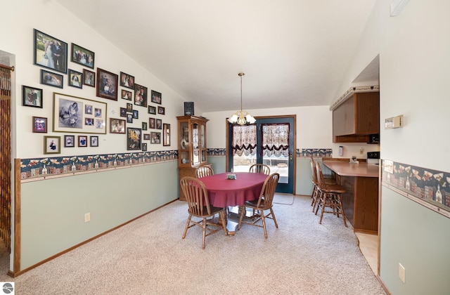 dining space featuring a notable chandelier, light colored carpet, baseboards, and vaulted ceiling