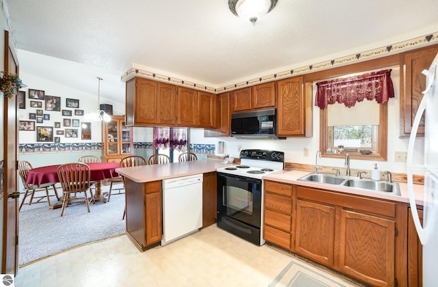 kitchen with light floors, vaulted ceiling, a peninsula, white appliances, and a sink