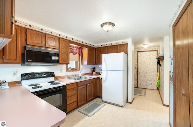 kitchen with light floors, freestanding refrigerator, a sink, electric range oven, and black microwave