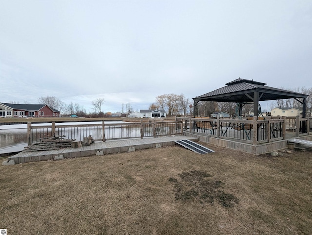 dock area with a gazebo, a deck with water view, and a yard