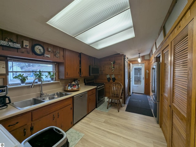 kitchen featuring a sink, stainless steel appliances, light wood-style floors, light countertops, and vaulted ceiling