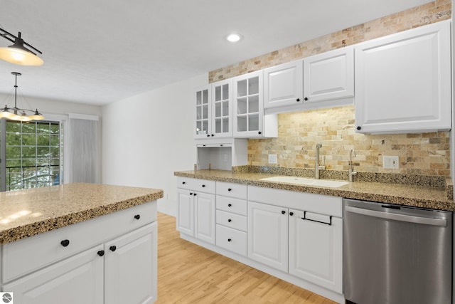 kitchen featuring a sink, glass insert cabinets, stainless steel dishwasher, light wood-type flooring, and backsplash