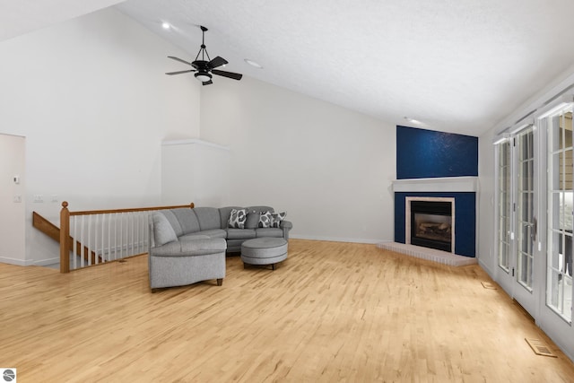 living area with visible vents, a brick fireplace, baseboards, and wood finished floors