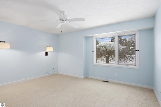 spare room with visible vents, baseboards, light carpet, a textured ceiling, and a ceiling fan