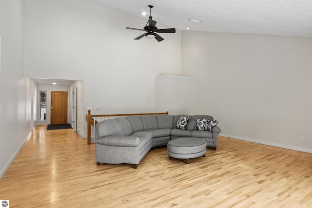 living room featuring light wood-type flooring, baseboards, high vaulted ceiling, and a ceiling fan