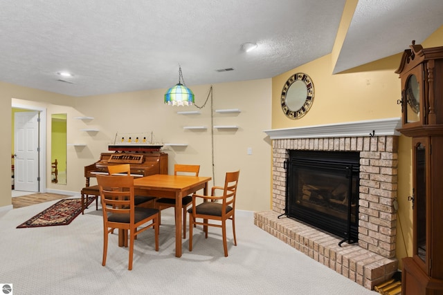 carpeted dining room with a brick fireplace, visible vents, baseboards, and a textured ceiling