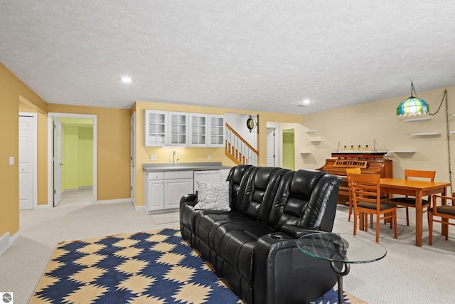 living area featuring light colored carpet, a textured ceiling, wet bar, and baseboards