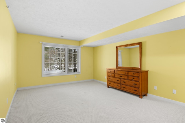 unfurnished bedroom with carpet flooring, baseboards, and a textured ceiling