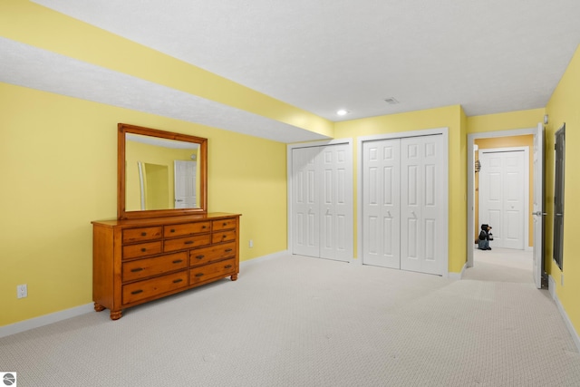 carpeted bedroom featuring baseboards and two closets