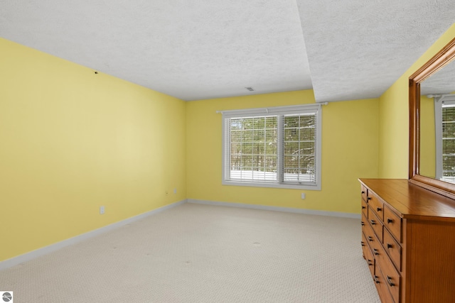 interior space featuring a textured ceiling, baseboards, and light carpet