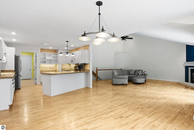 kitchen featuring white microwave, open floor plan, a fireplace with raised hearth, and freestanding refrigerator