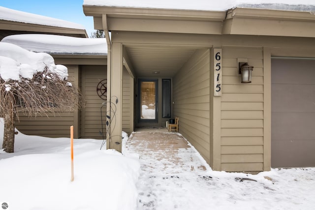 snow covered property entrance with a garage