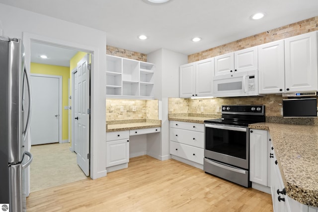 kitchen with white cabinetry, backsplash, appliances with stainless steel finishes, and built in study area