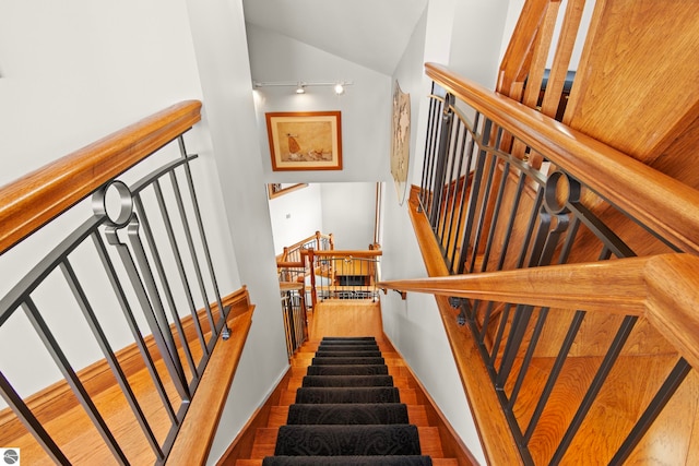 stairs with lofted ceiling, wood finished floors, and baseboards