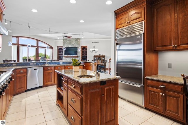 kitchen featuring a sink, stainless steel appliances, stone counters, and light tile patterned floors