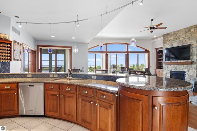 kitchen with brown cabinetry, a sink, dishwasher, open floor plan, and backsplash